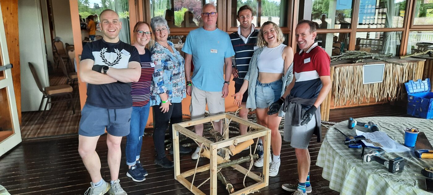 “Corporate group engaging in a CSR activity overlooking the wildlife habitats at Woburn Safari Park.” “Employees collaborating during a team building session at Woburn Safari Park’s Safari Lodge event space.”