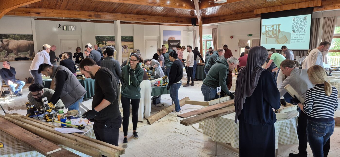 “Corporate group engaging in a CSR activity overlooking the wildlife habitats at Woburn Safari Park.” “Employees collaborating during a team building session at Woburn Safari Park’s Safari Lodge event space.”
